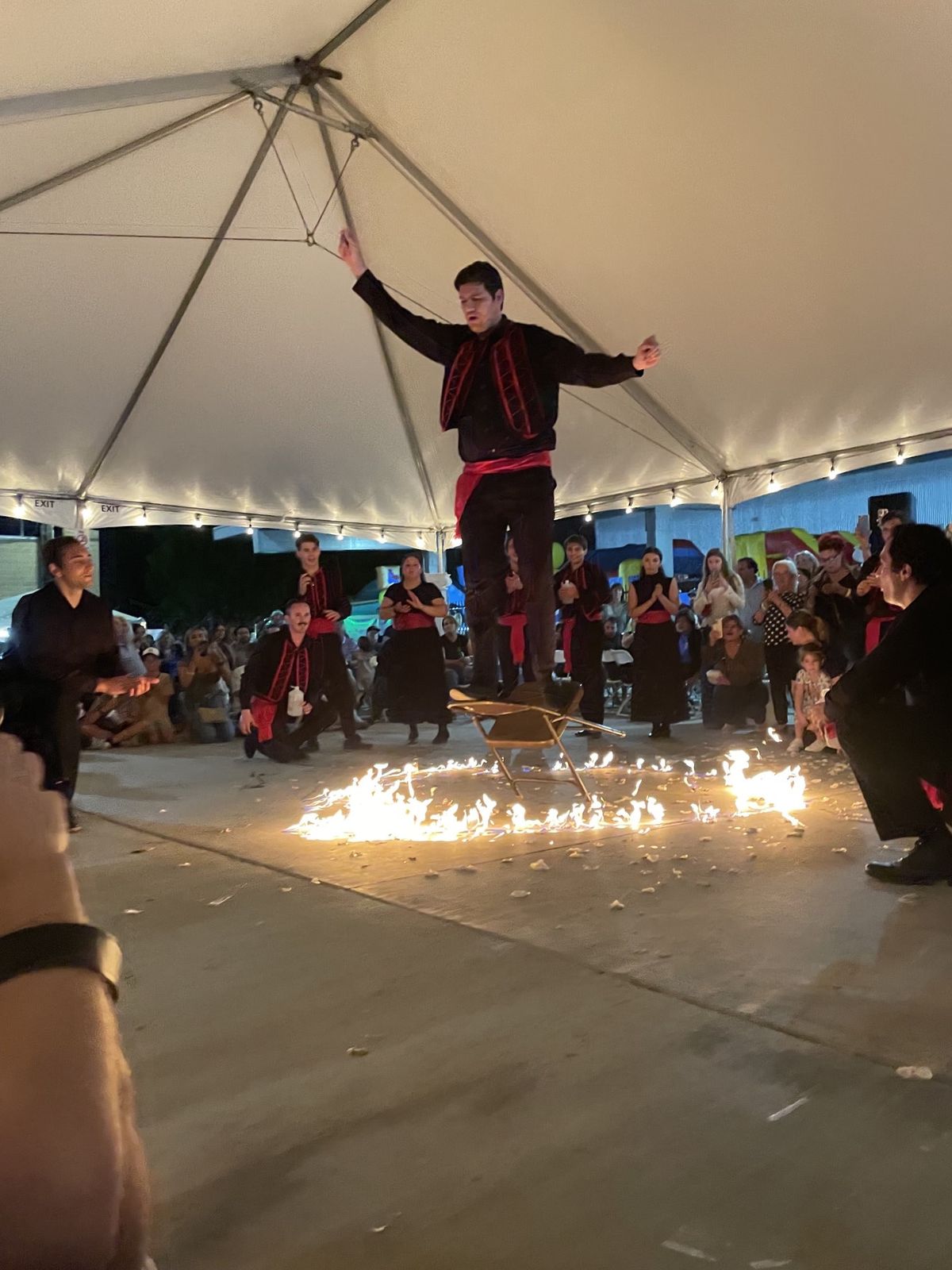 Dancer standing on a chair over a ring of fire under the tent