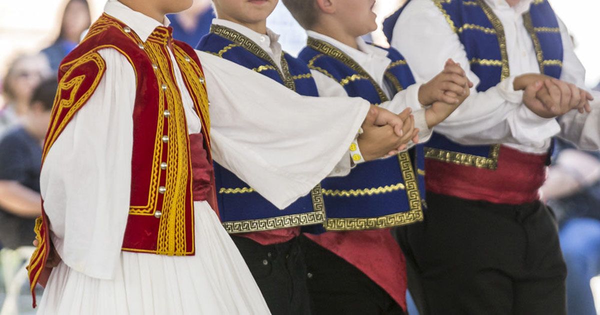 Children in traditional Greek dress holding hands to dance