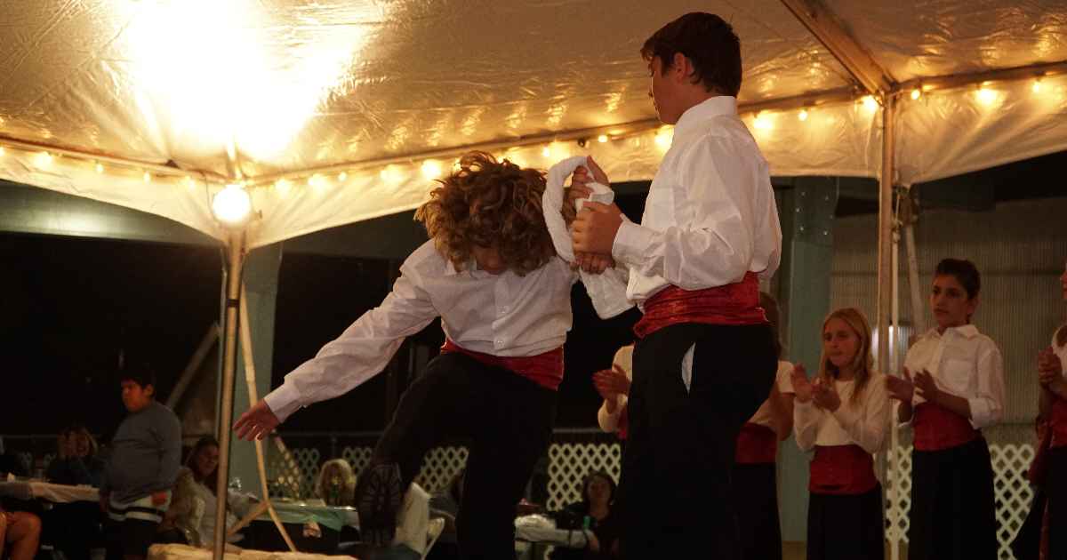 Young dancers sharing a handkerchief under the tent